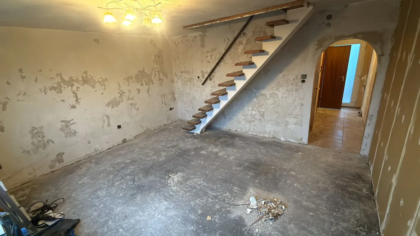 Treppenaufgang der Maisonette-Wohnung in Düsseldorf-Stockum vor der Renovierung mit abgeschlagenem Putz und rohem Estrich
