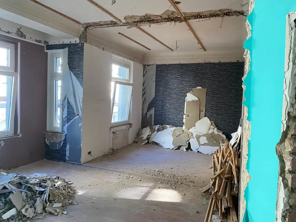Wohnraum in Düsseldorf-Bilk im Rückbau, entfernte Wandverkleidung, offene Decke und Bauschutt auf dem Boden